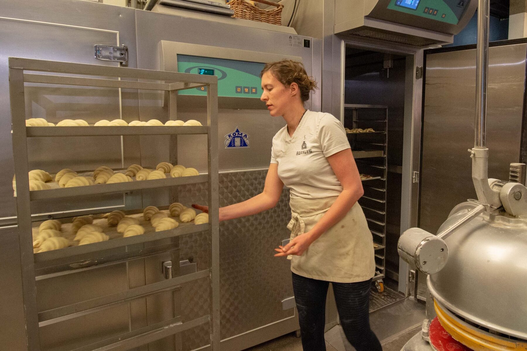 Bakker rijdt een ovenwagen met deegwaren de rijskast in