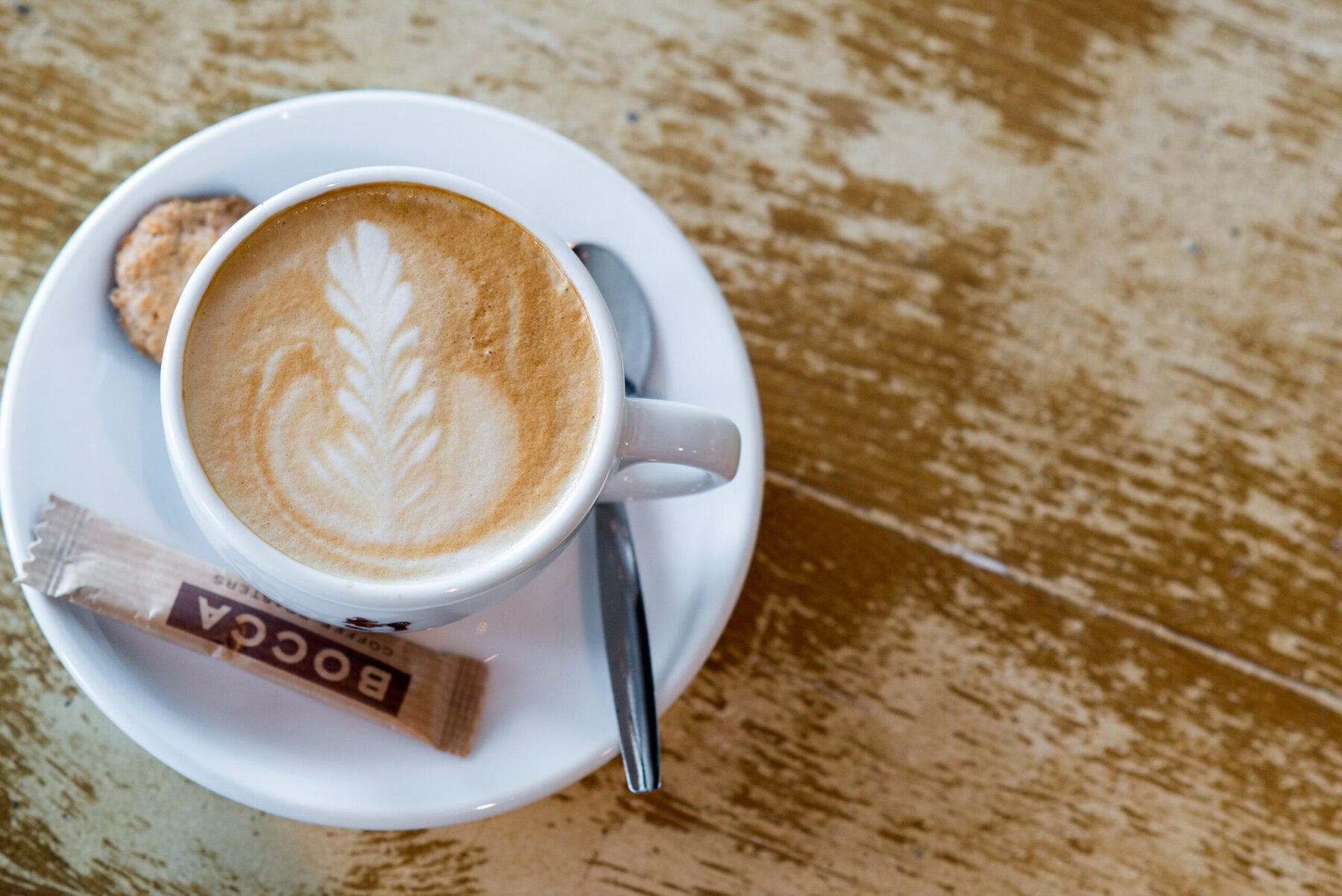 Cappuccino met latte art en een zakje Bocca-suiker